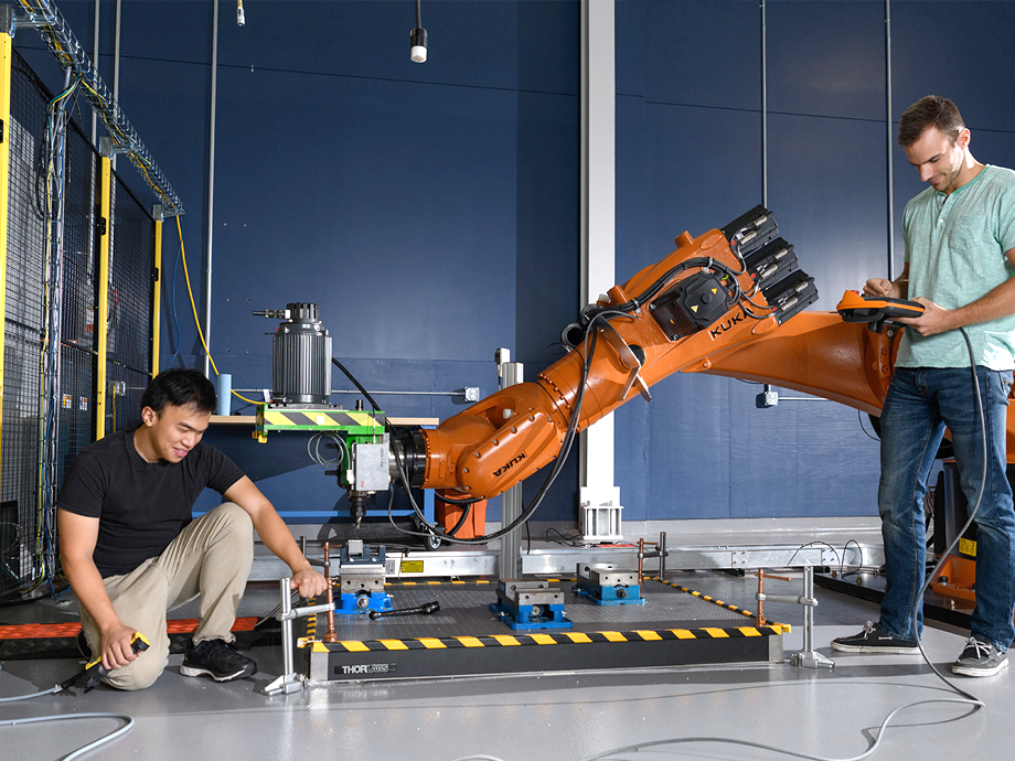 two students working on a rather large robotic arm