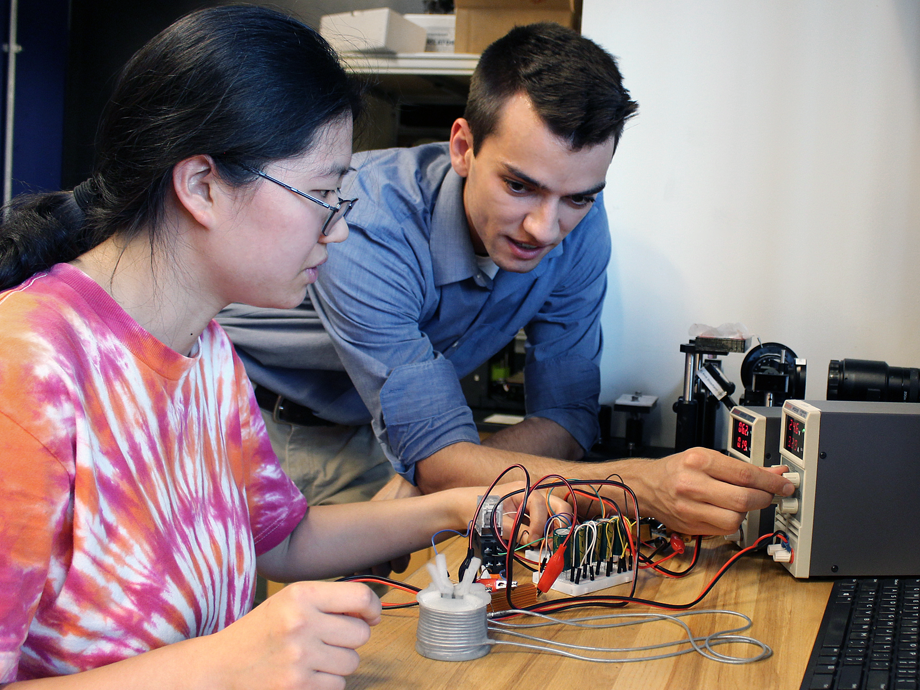 a man and women working on a small robot on a table top